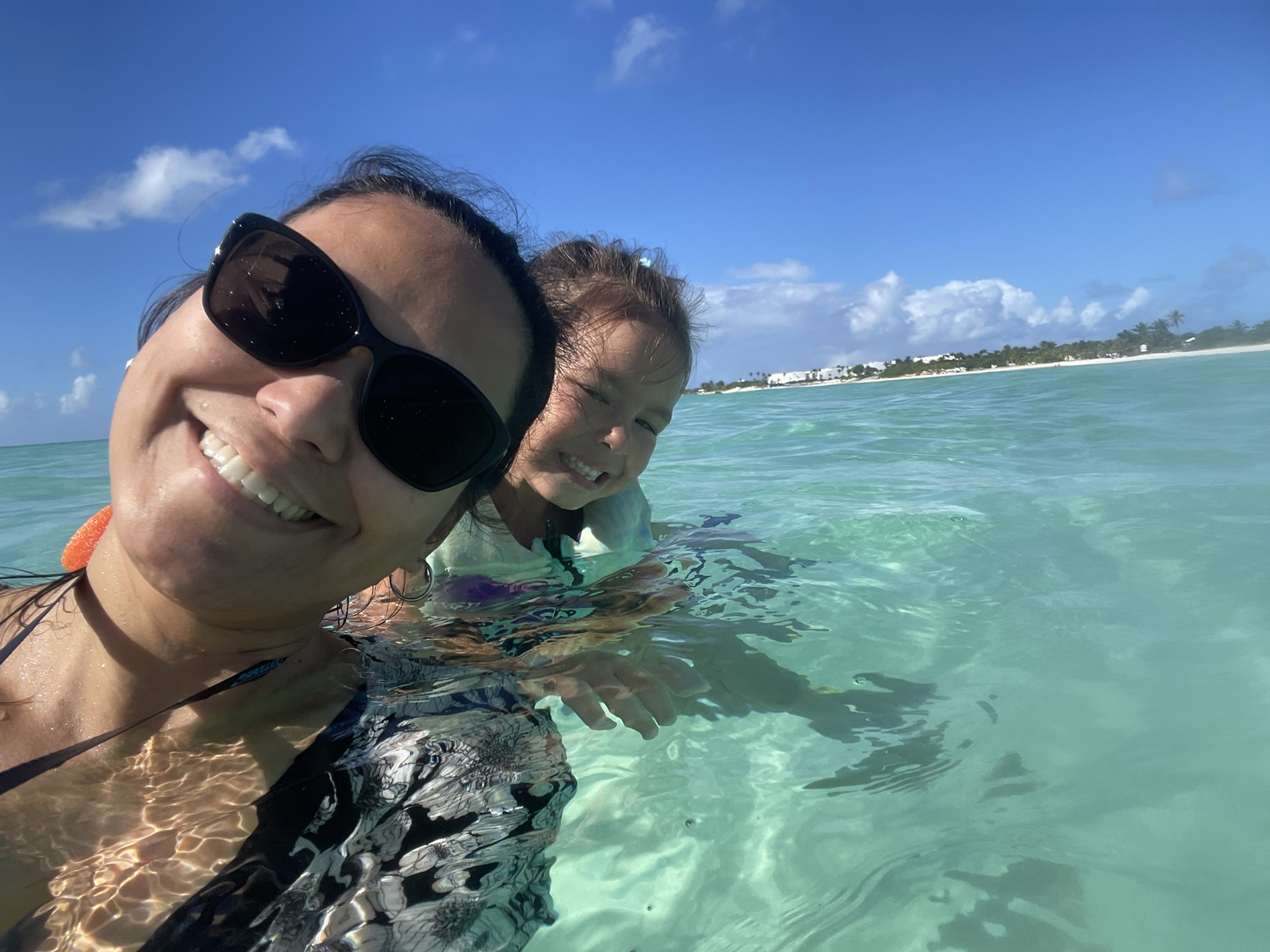 Work-from-home family travel in Anguilla — parent swimming with daughter in the crystal-clear waters of Rendezvous Bay.