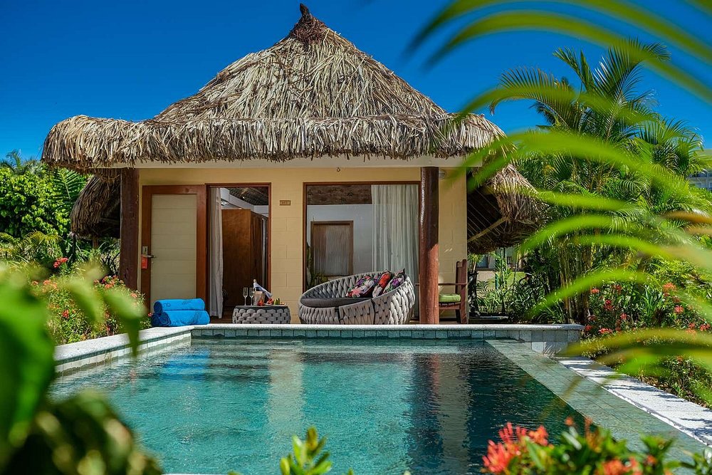 Private bungalow with pool framed by palm leaves, surrounded by tropical gardens along Fiji’s South Pacific coast, ideal for relaxing luxury getaways.