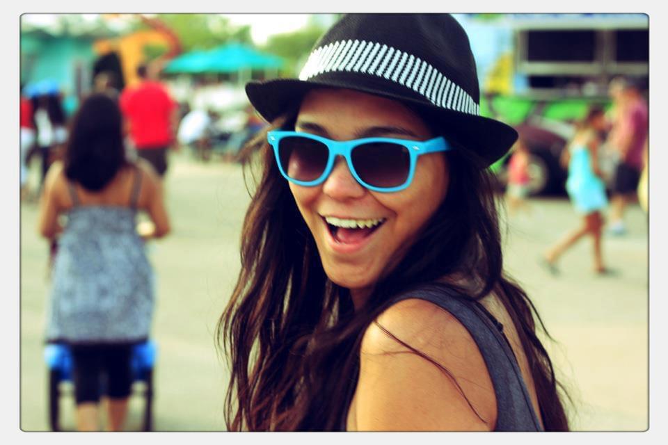 Anne Valdez smiling with blue sunglasses and black fedora at Cedar Point amusement park, capturing a joyful, candid moment that introduces the travel agent behind This Mamma Travels.