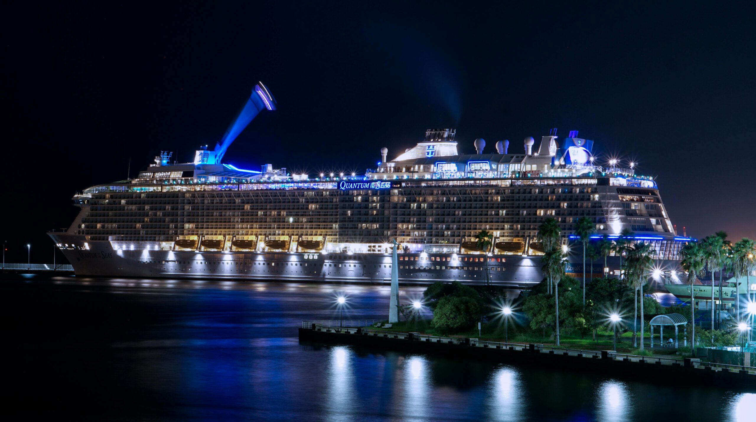 Illuminated cruise ship docked in harbor at night, representing Caribbean luxury all-inclusive cruise vacations.