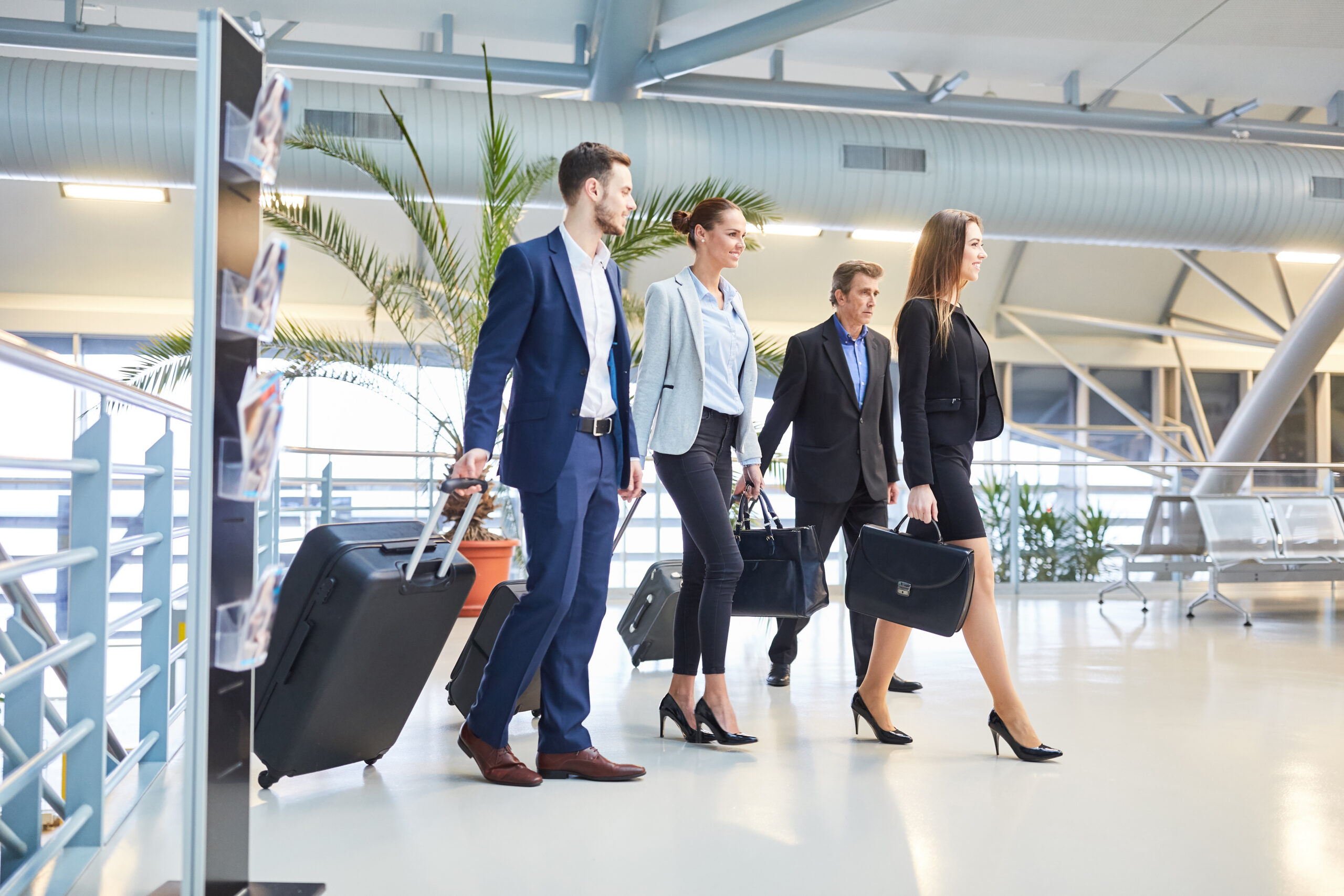 Business professionals with luggage walking through an airport, representing corporate and business travel services.