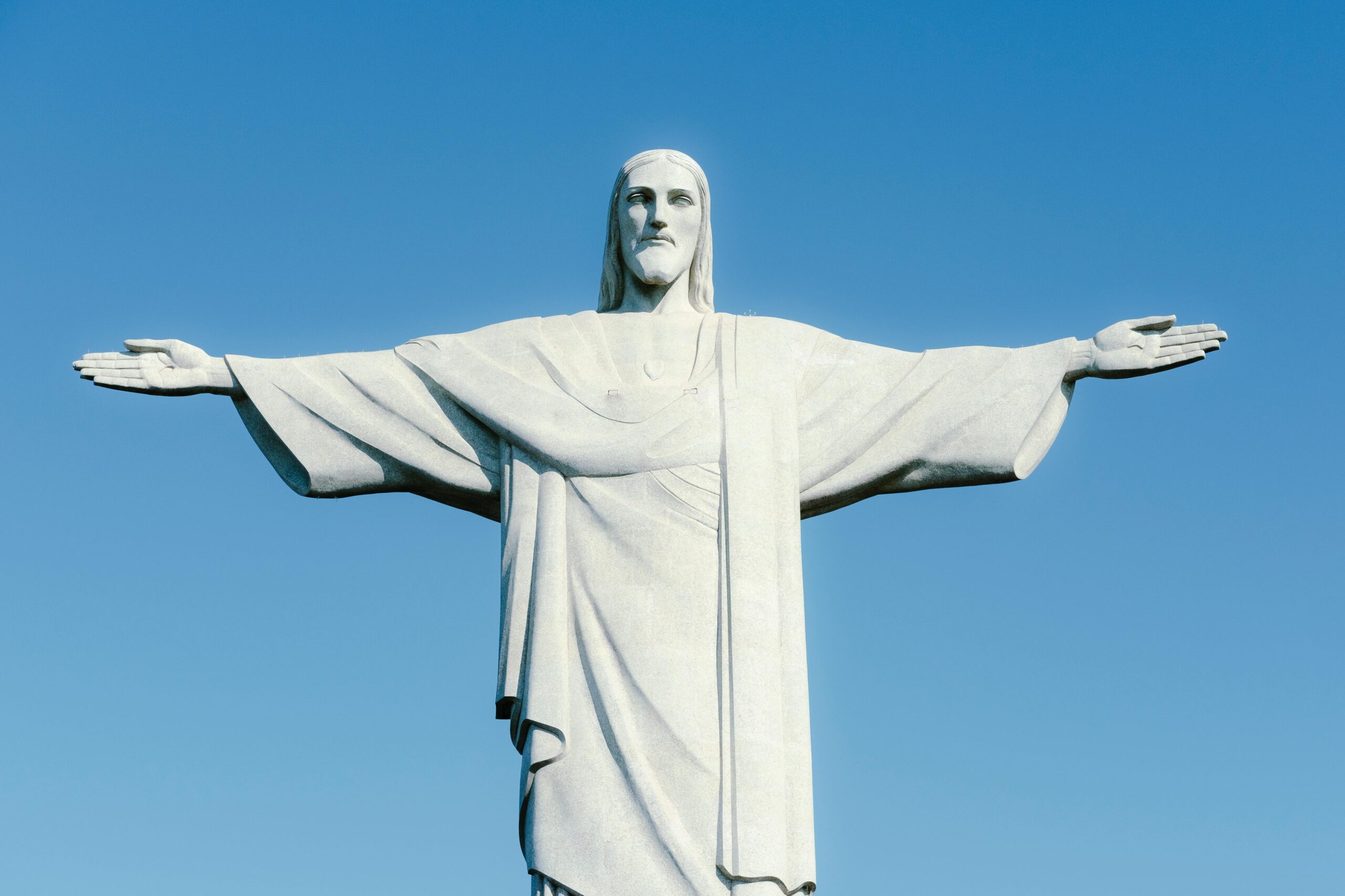 Christ the Redeemer statue in Rio de Janeiro on a clear blue sky day, representing faith-based travel opportunities.