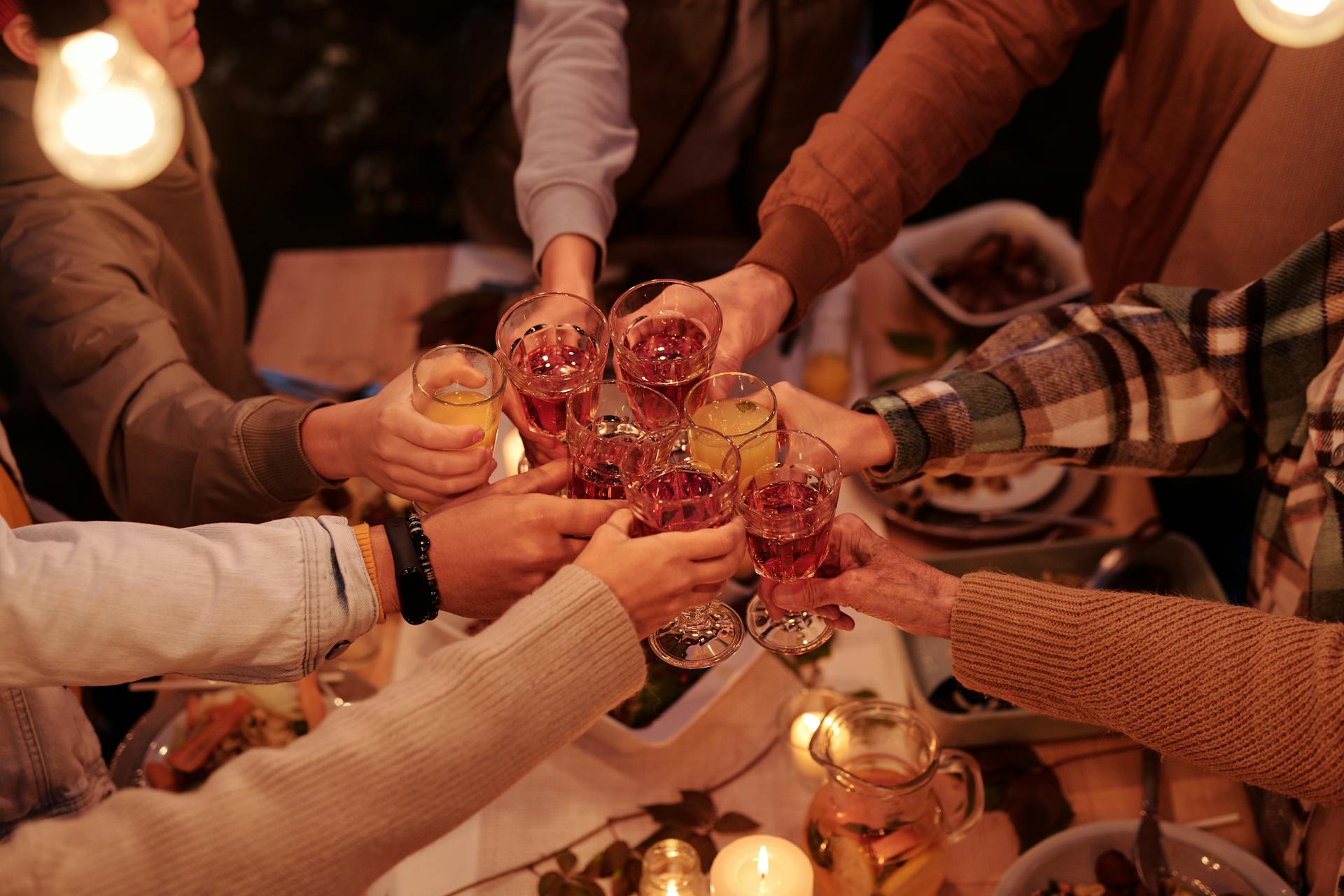 Group raising glasses in a toast over dinner, symbolizing family reunion vacation and group travel packages.