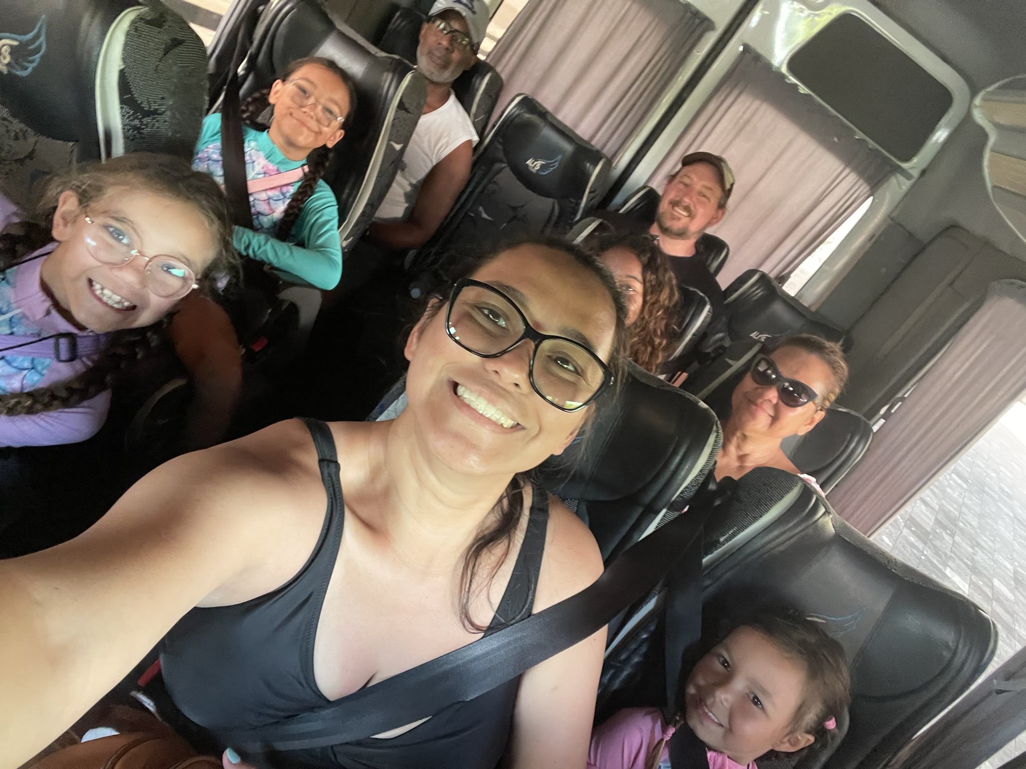 Family taking a group selfie in the back of a passenger van after a long day of sailing, sandy, sunburned, and smiling after a full day of adventure.