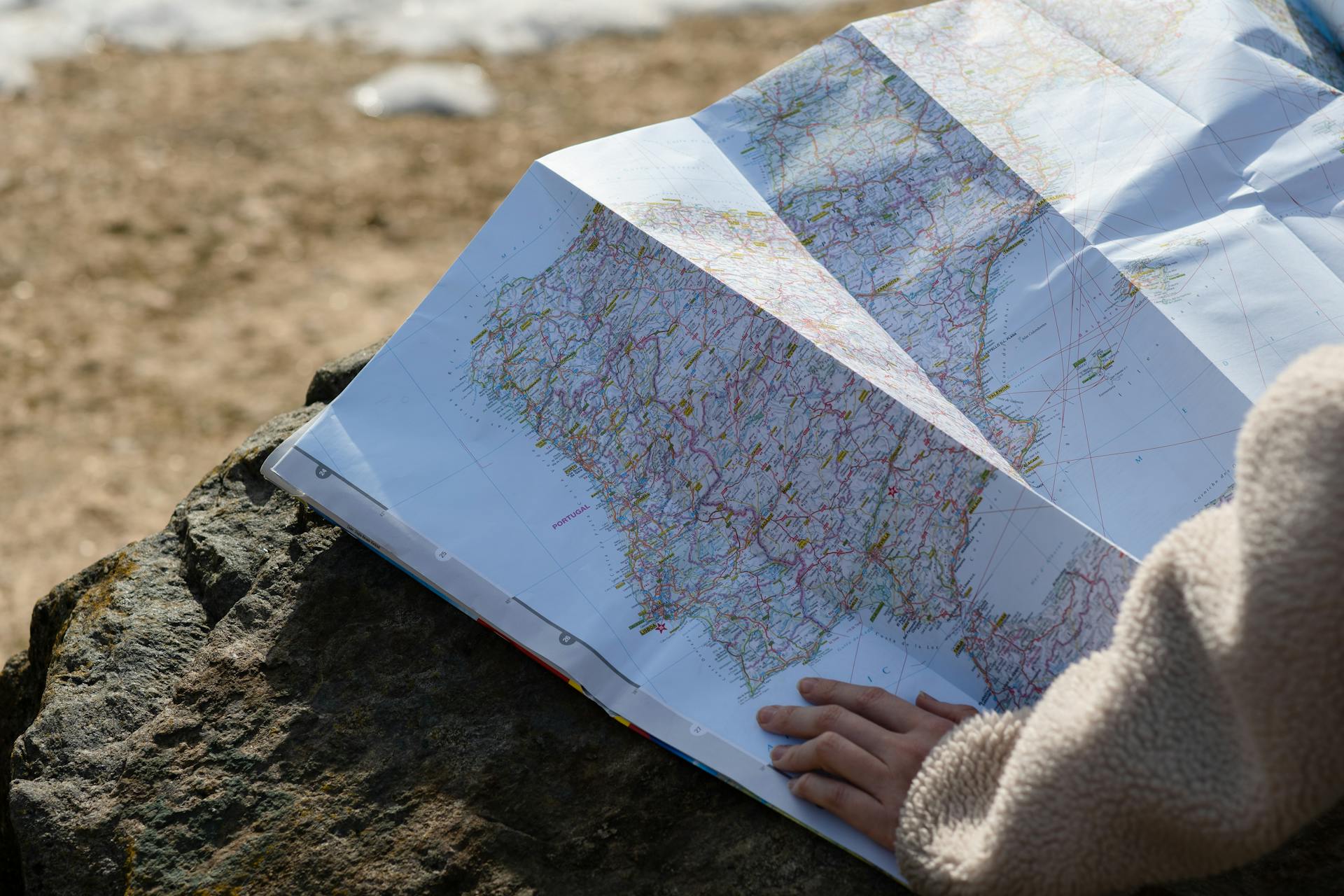 A person stretching a map over a large bolder representing navigating through unlocking their unforgettable experience