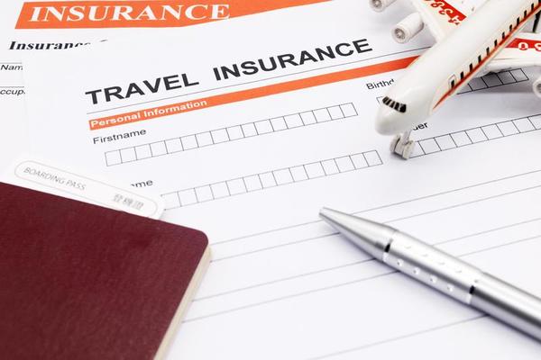 Travel insurance form with pen and toy airplane, symbolizing vacation protection and international travel coverage.