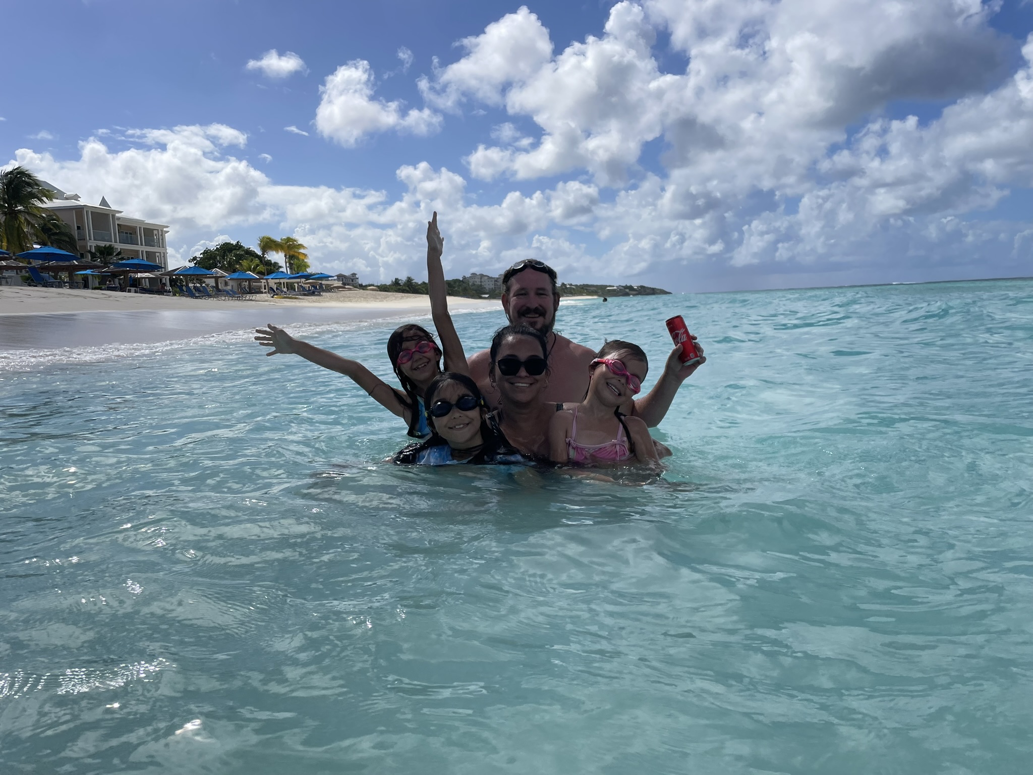 Travelers swimming in Rendezvous Bay, Anguilla, with tropical ocean horizon and beach umbrellas, symbolizing the joy of unlocking unforgettable travel experiences.