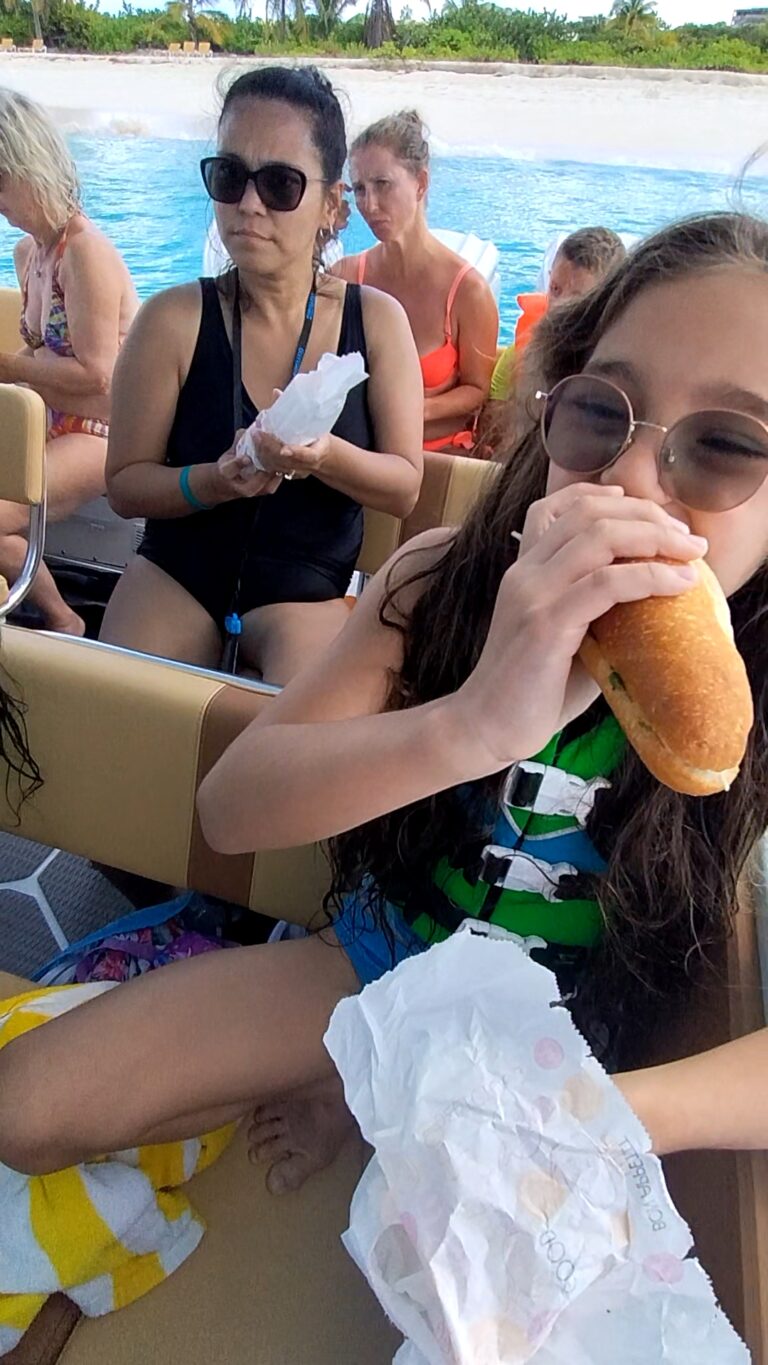 Child eating a large sandwich on a boat during an island-hopping, Shoal Bay Anguilla speedboat tour.