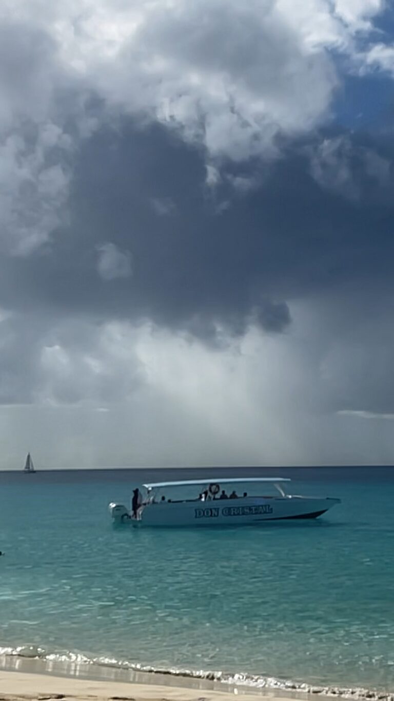 Speedboat floating on glass calm water at Meads Bay Anguilla with sunlight breaking through dark clouds.