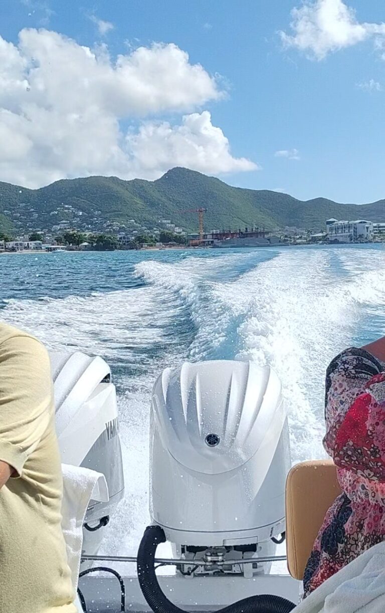Triple outboard engines powering a speedboat during a Saint Martin to Anguilla speedboat tour, leaving a bright white wake across deep blue Caribbean water near the marina.